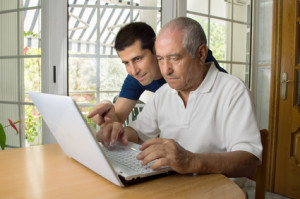 Senior man teaching laptop to his son